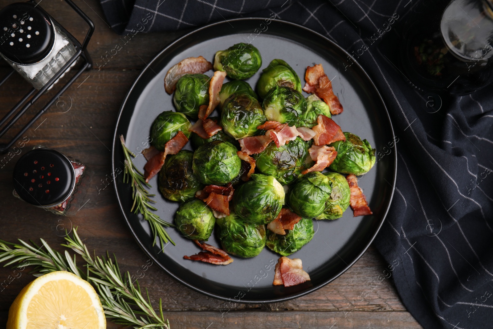 Photo of Delicious roasted Brussels sprouts, bacon, rosemary and lemon on wooden table, flat lay