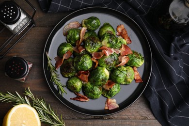 Photo of Delicious roasted Brussels sprouts, bacon, rosemary and lemon on wooden table, flat lay
