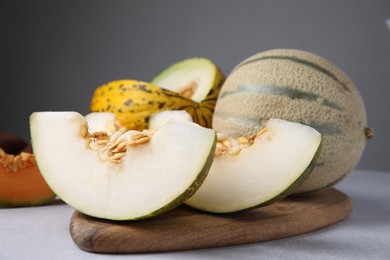 Photo of Tasty colorful ripe melons on light grey table, closeup