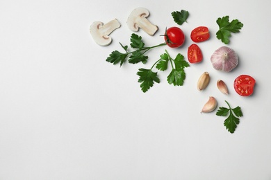 Flat lay composition with green parsley, garlic, tomatoes and mushrooms on light background