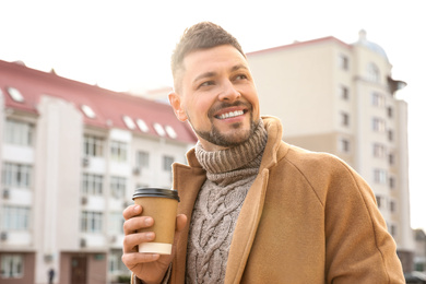 Photo of Man with cup of coffee on city street in morning