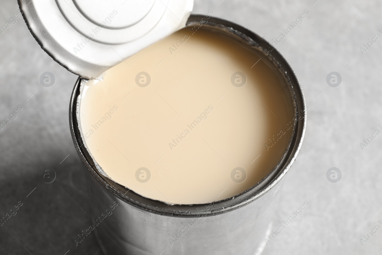 Photo of Tin can with condensed milk on grey background, closeup. Dairy product