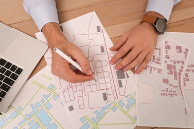 Photo of Professional cartographer working with cadastral map at wooden table, top view