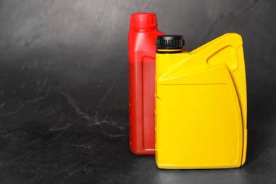 Photo of Motor oil in different canisters on black background, space for text