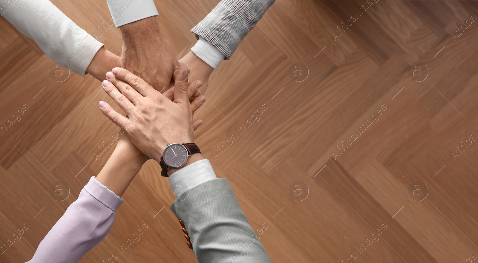 People holding hands together over wooden background, top view with space for text. Unity concept Photo of People holding hands together over wooden background, top view with space for text. Unity concept