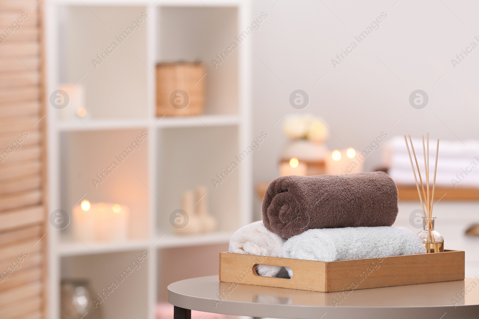 Photo of Tray with towels and reed air freshener on table in spa salon. Space for text