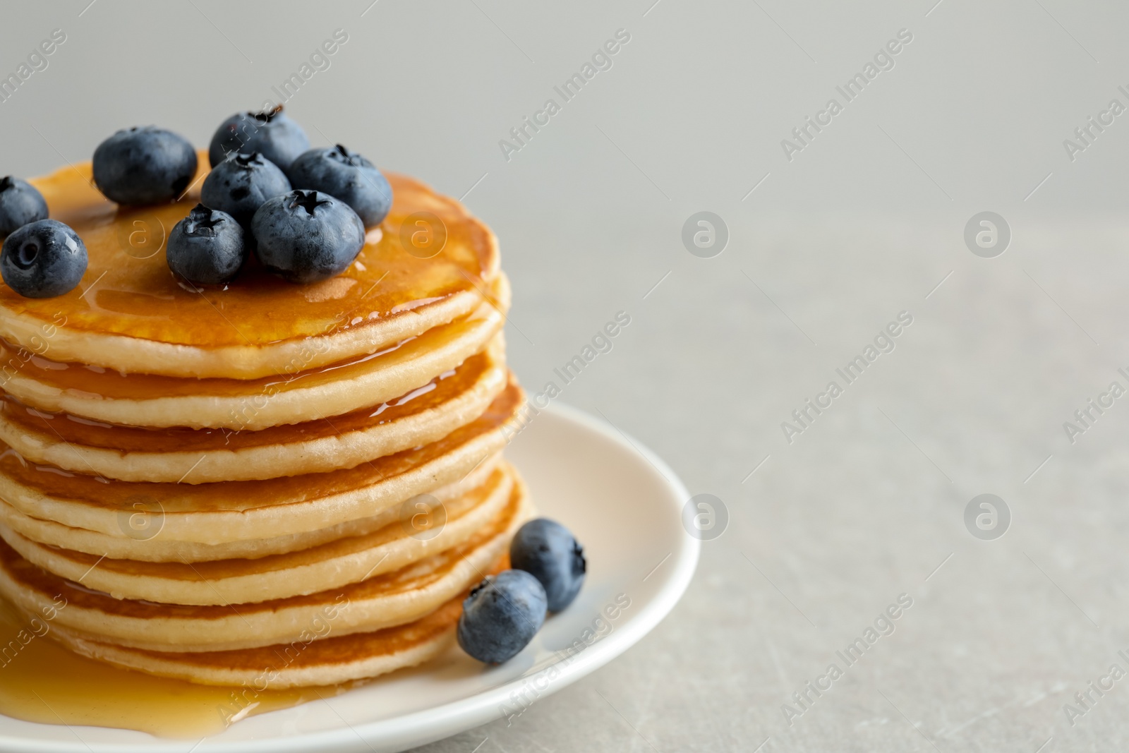Photo of Plate with pancakes and berries on grey background, closeup
