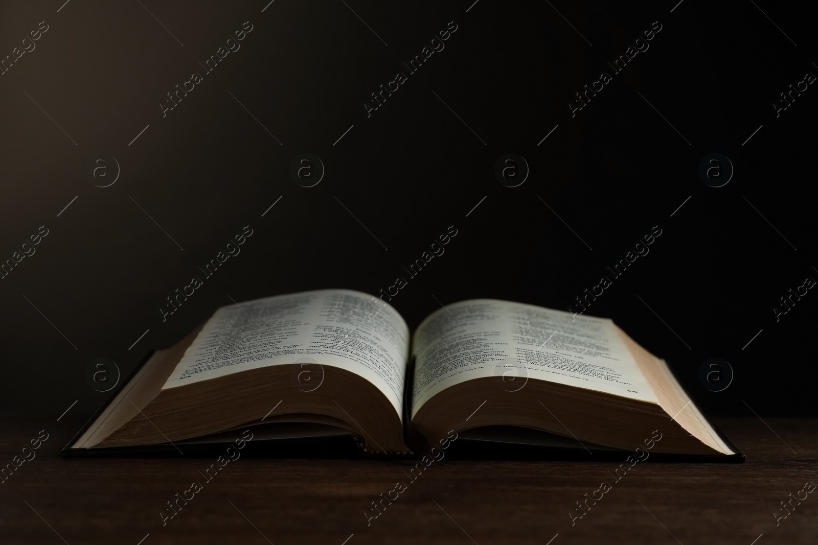 Photo of Open hardcover Bible on wooden table, space for text. Religious book