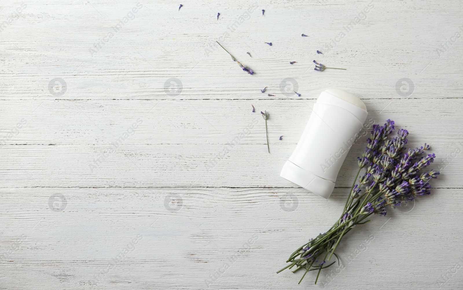 Photo of Female deodorant and lavender flowers on white wooden background, flat lay. Space for text