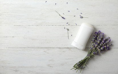 Female deodorant and lavender flowers on white wooden background, flat lay. Space for text