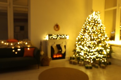 Photo of Stylish fireplace between Christmas tree and sofa in cosy room, blurred view