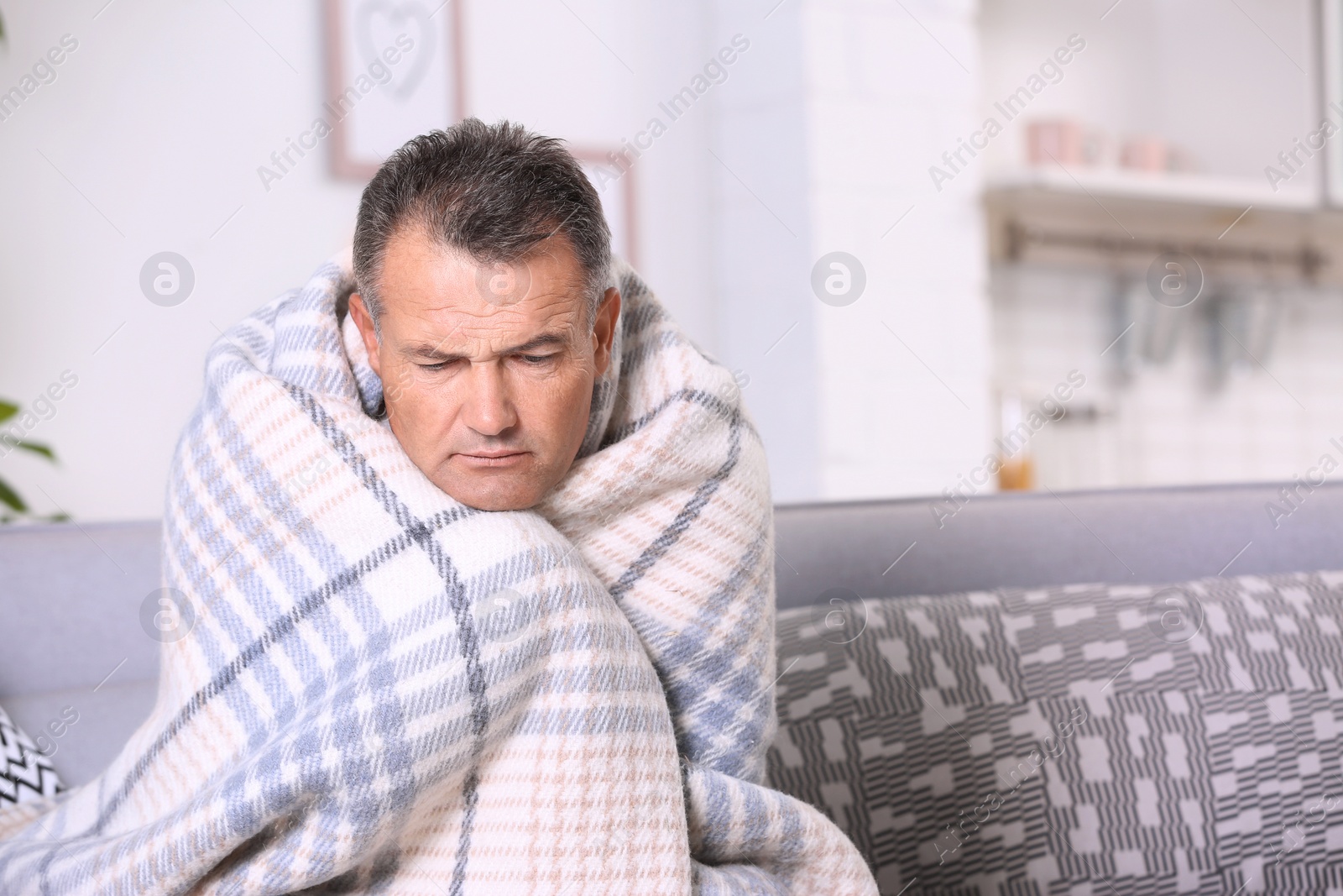 Photo of Man suffering from cough and cold on sofa at home. Space for text