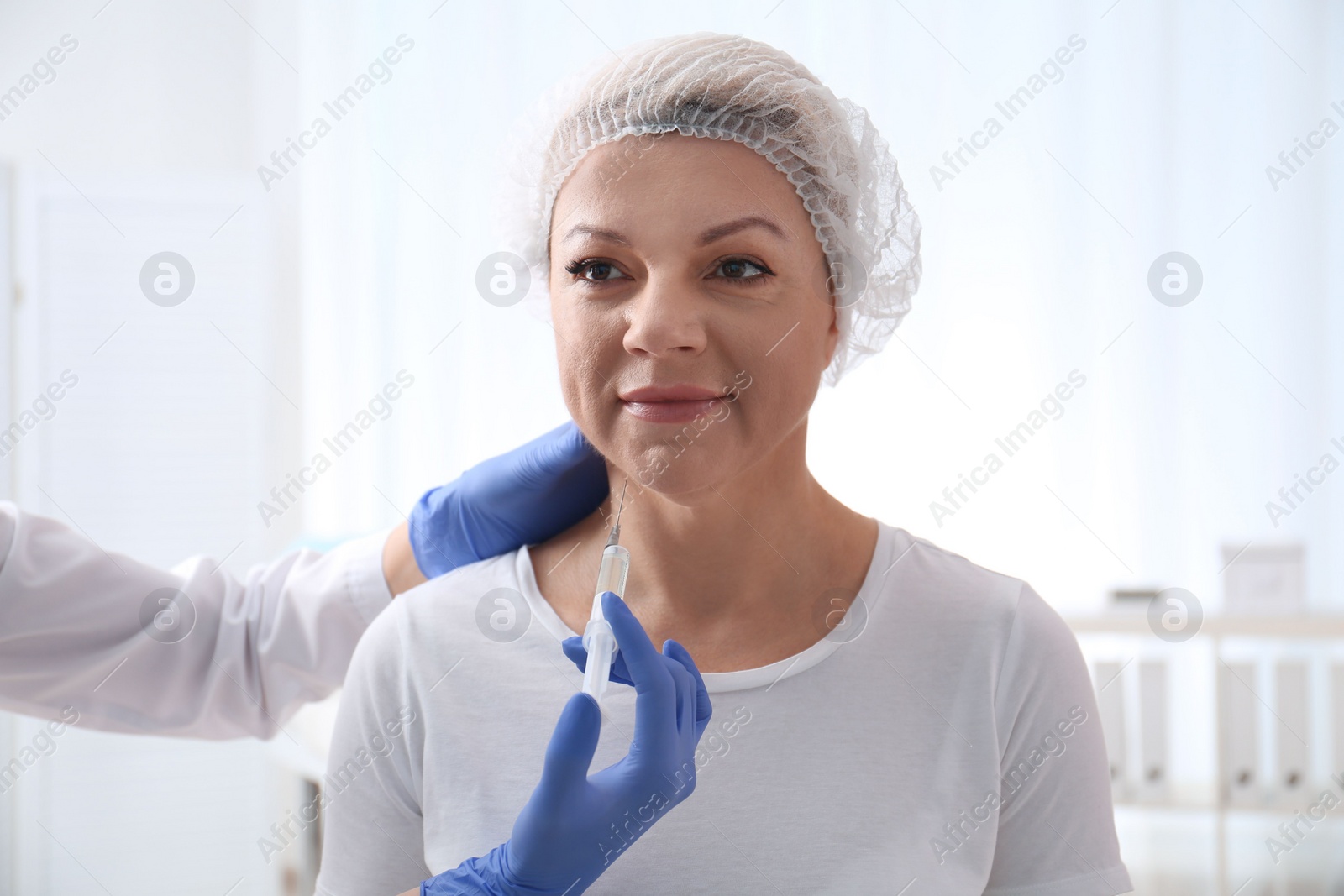 Photo of Mature woman with double chin receiving injection in clinic