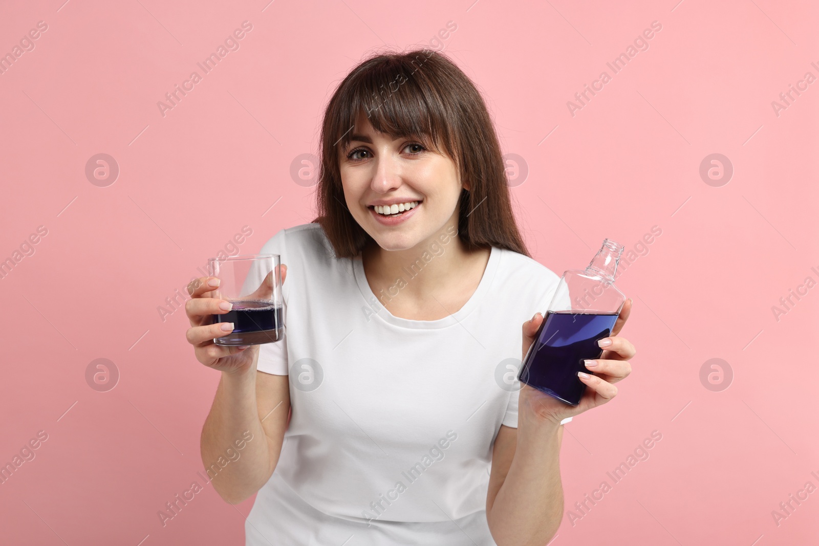 Photo of Young woman with mouthwash on pink background