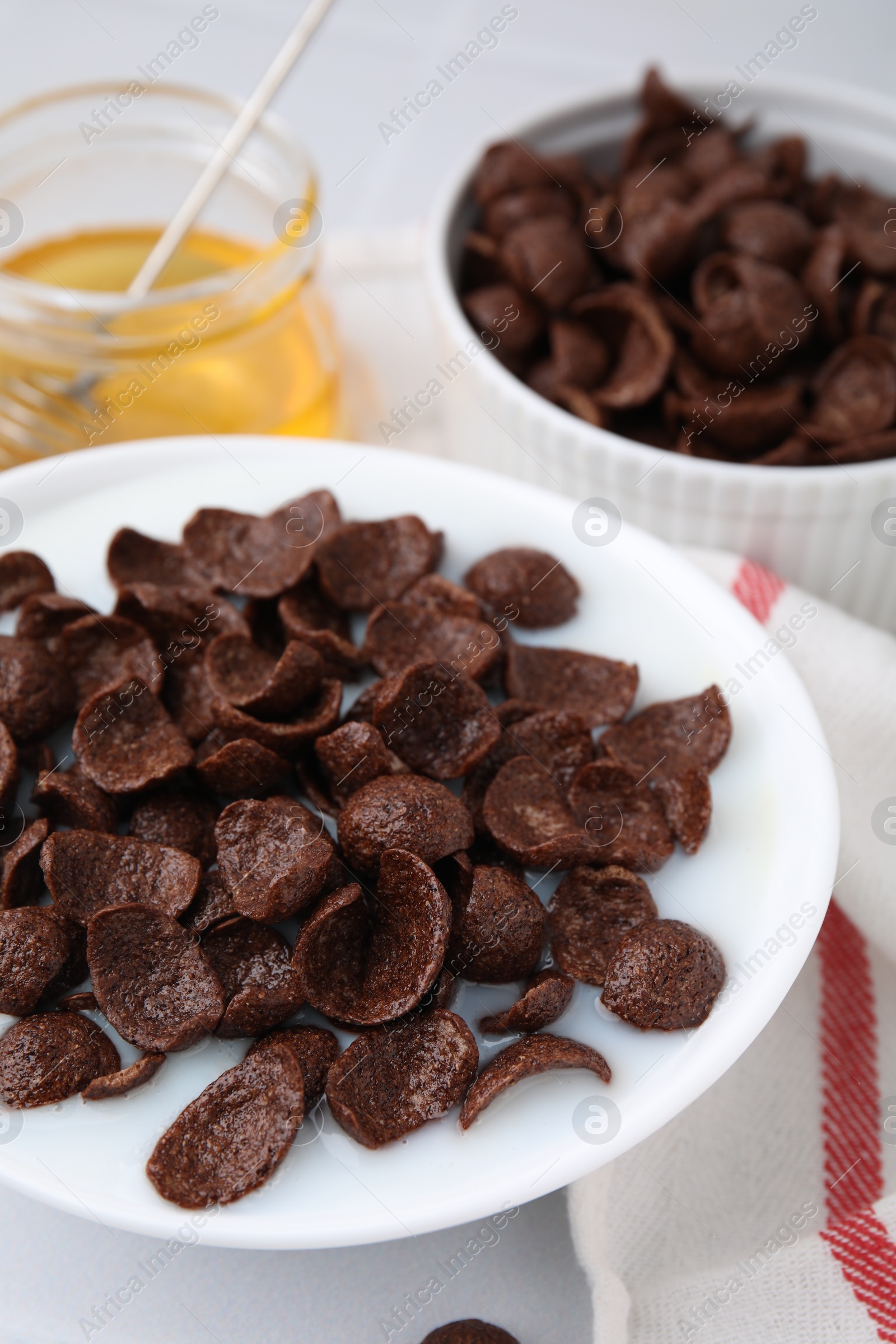 Photo of Breakfast cereal. Chocolate corn flakes and milk in bowl on white table, closeup