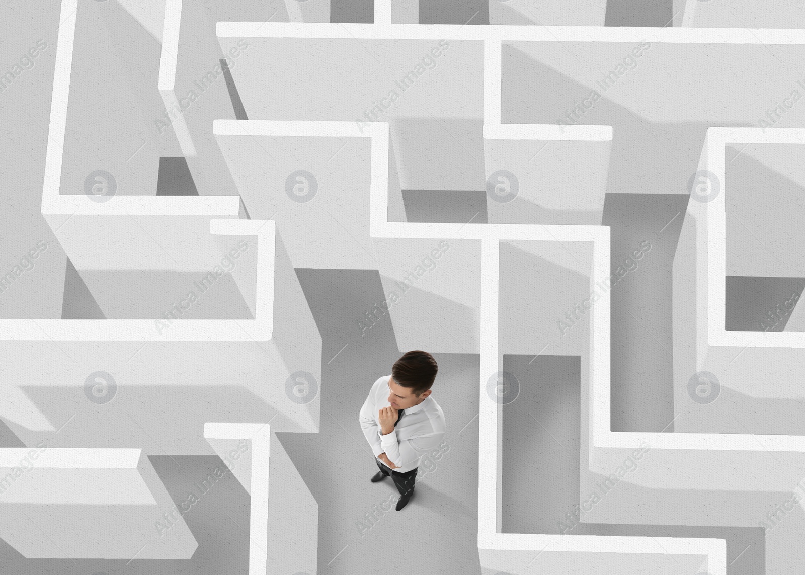 Image of Businessman trying to find way out of maze, above view