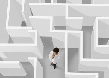 Businessman trying to find way out of maze, above view