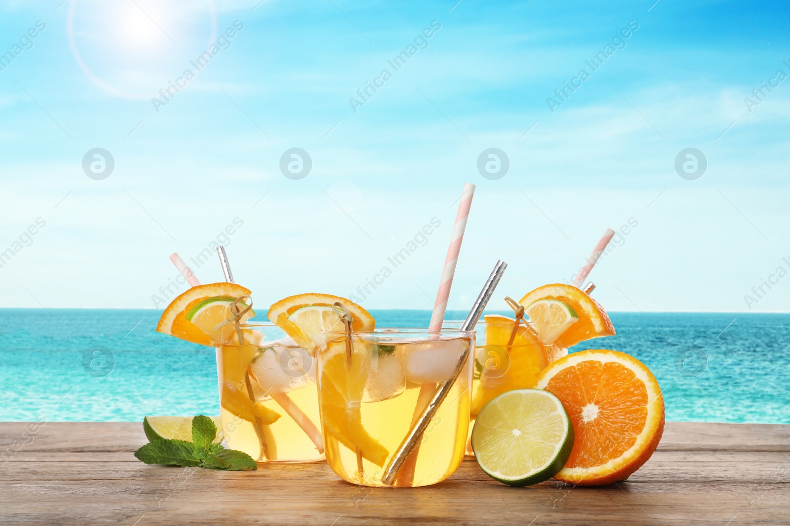 Image of Tasty refreshing drink on wooden table against sea