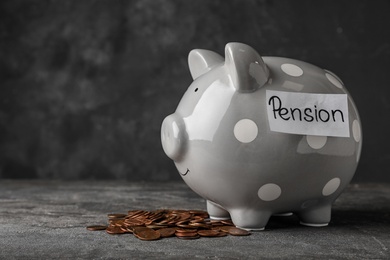 Piggy bank with word PENSION and coins on table. Space for text