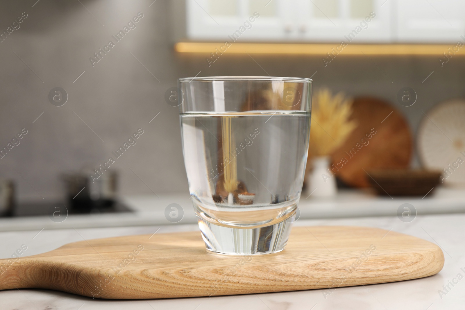 Photo of Filtered water in glass on white table in kitchen, closeup