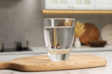 Photo of Filtered water in glass on white table in kitchen, closeup