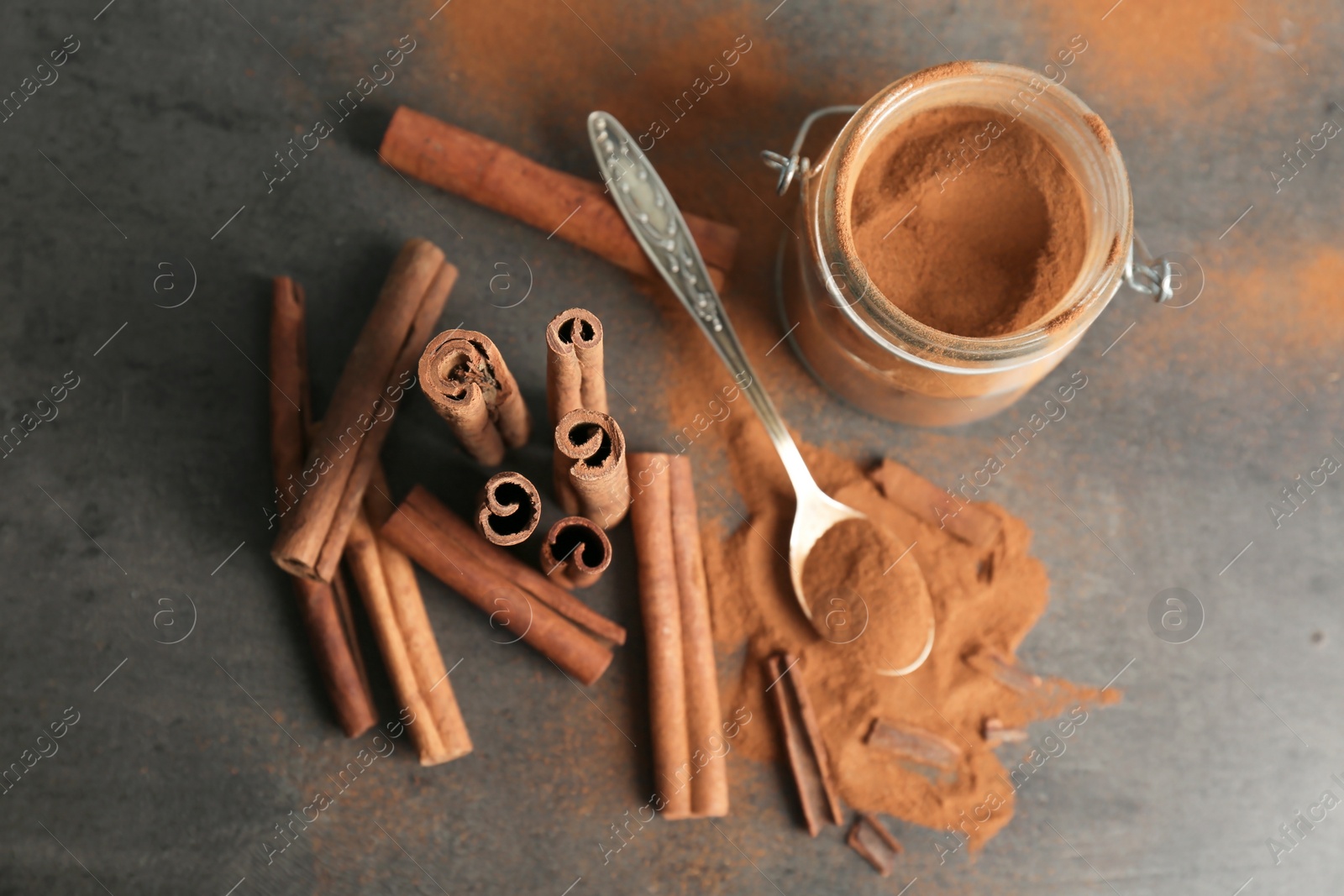 Photo of Composition with aromatic cinnamon powder and sticks on grey background