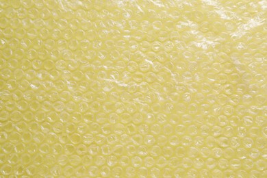 Photo of Transparent bubble wrap on yellow background, top view