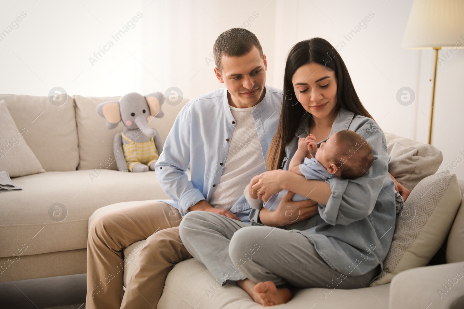 Photo of Happy family with cute baby on sofa at home