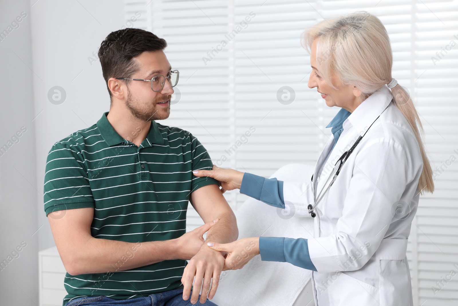 Photo of Doctor checking patient's pulse during consultation in clinic