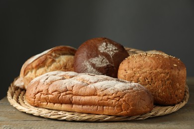 Wicker basket with different types of fresh bread on wooden table