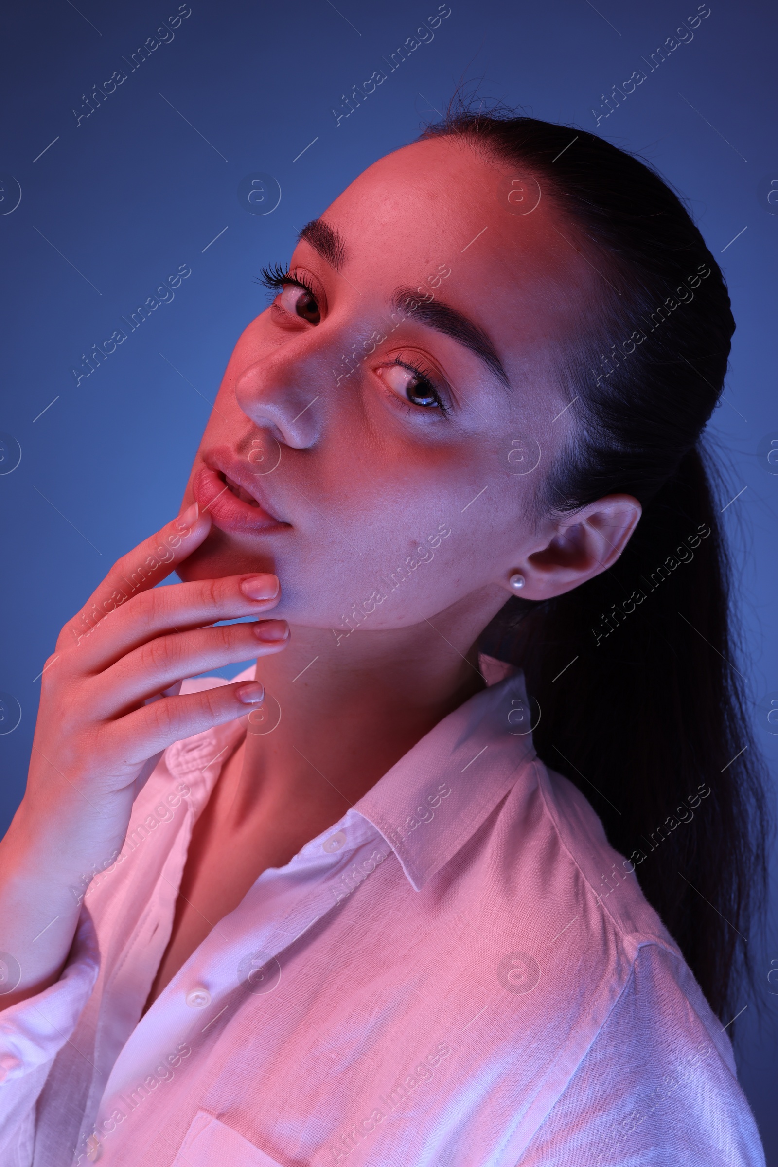 Photo of Portrait of beautiful young woman posing on blue background with neon lights