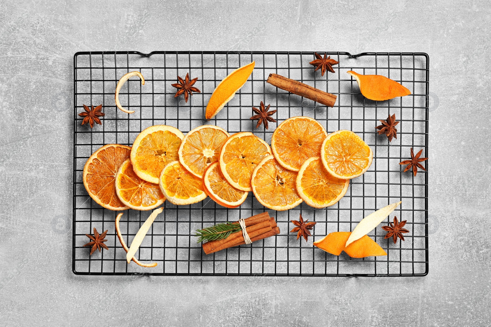 Photo of Flat lay composition with dry orange slices, anise stars and cinnamon sticks on light grey table