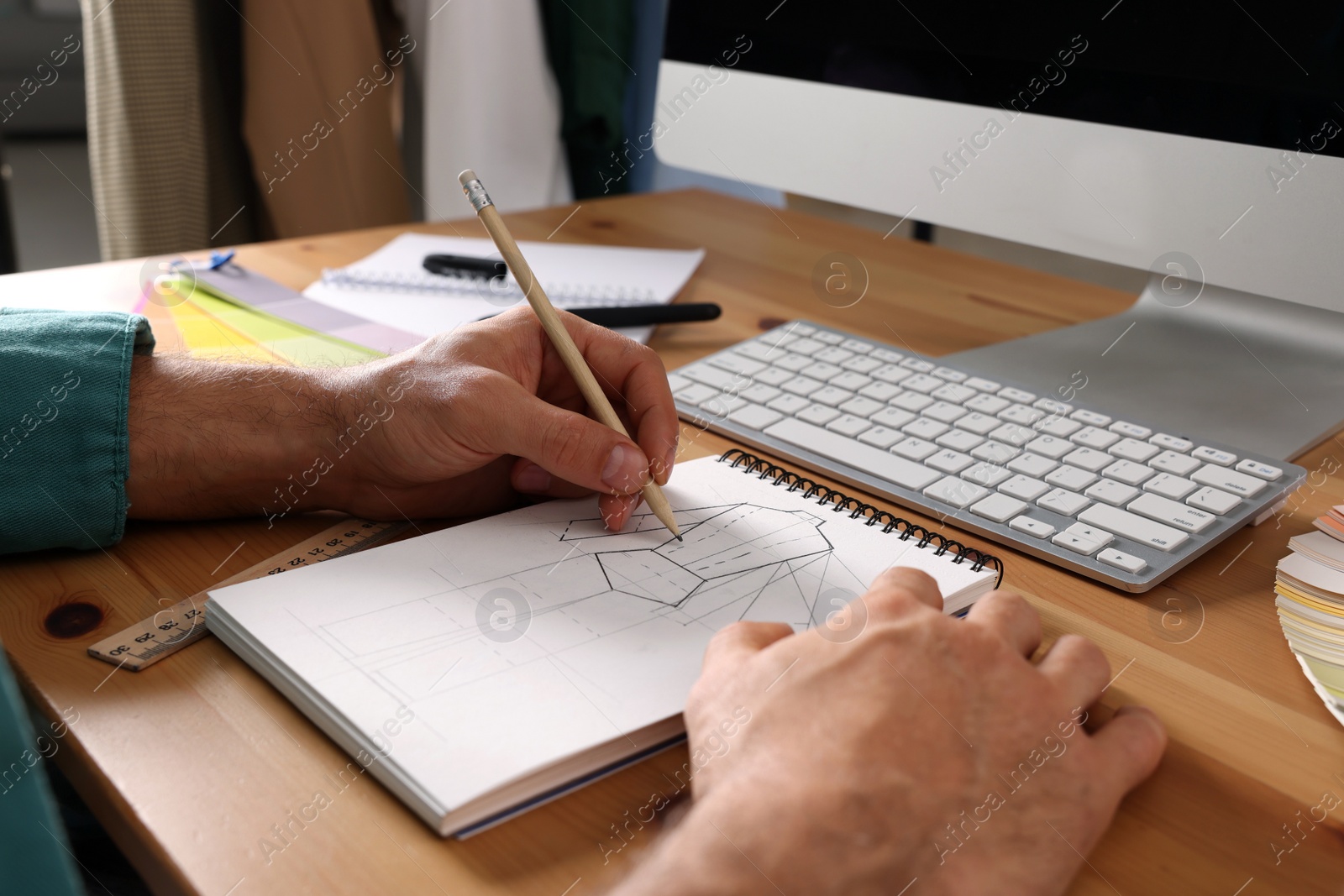 Photo of Man drawing in sketchbook with pencil at wooden table, closeup