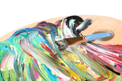 Photo of Palette with paints and brush on white background, closeup. Artist equipment