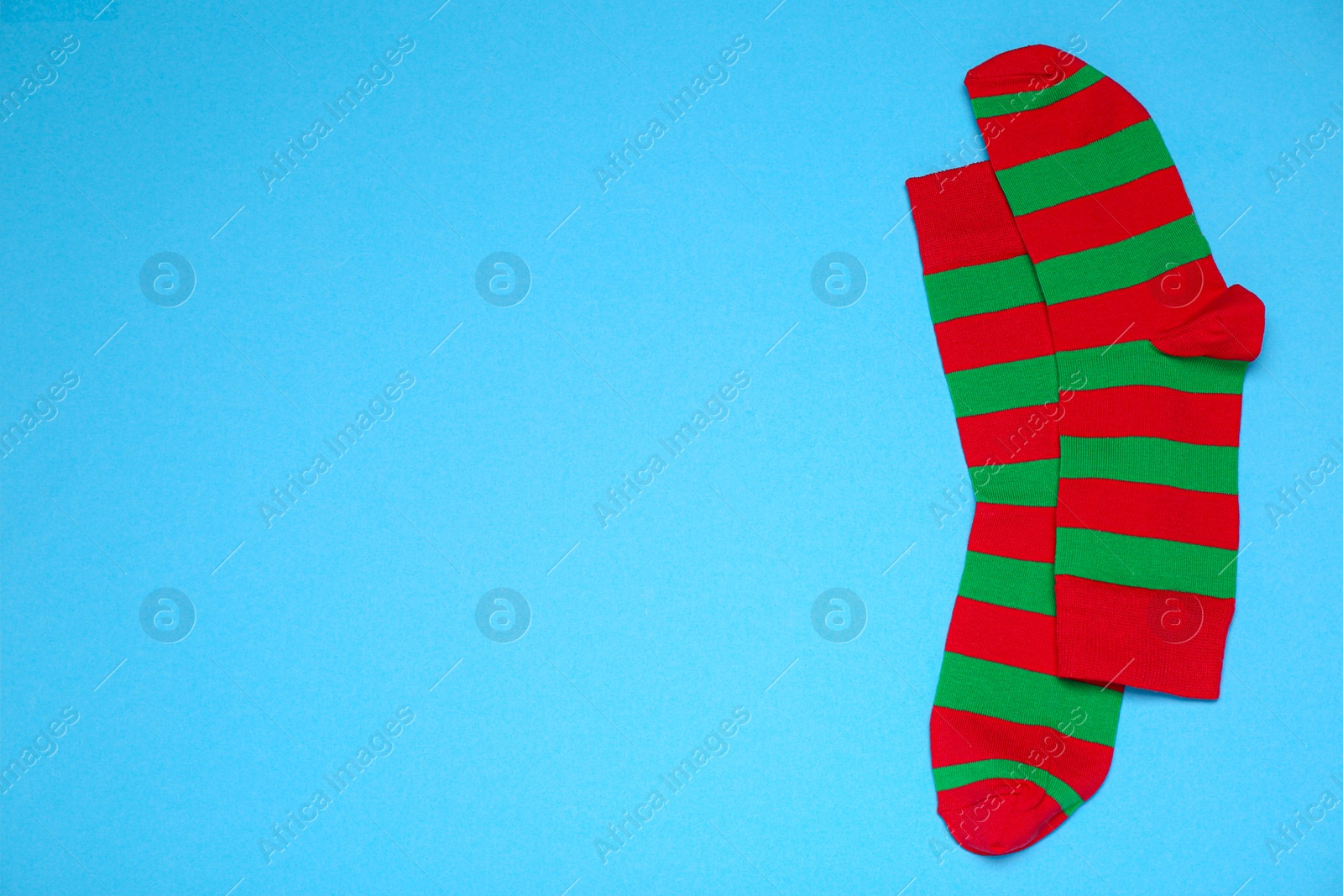 Photo of Pair of striped socks on light blue background, flat lay. Space for text