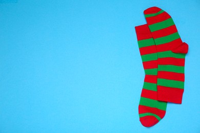 Pair of striped socks on light blue background, flat lay. Space for text