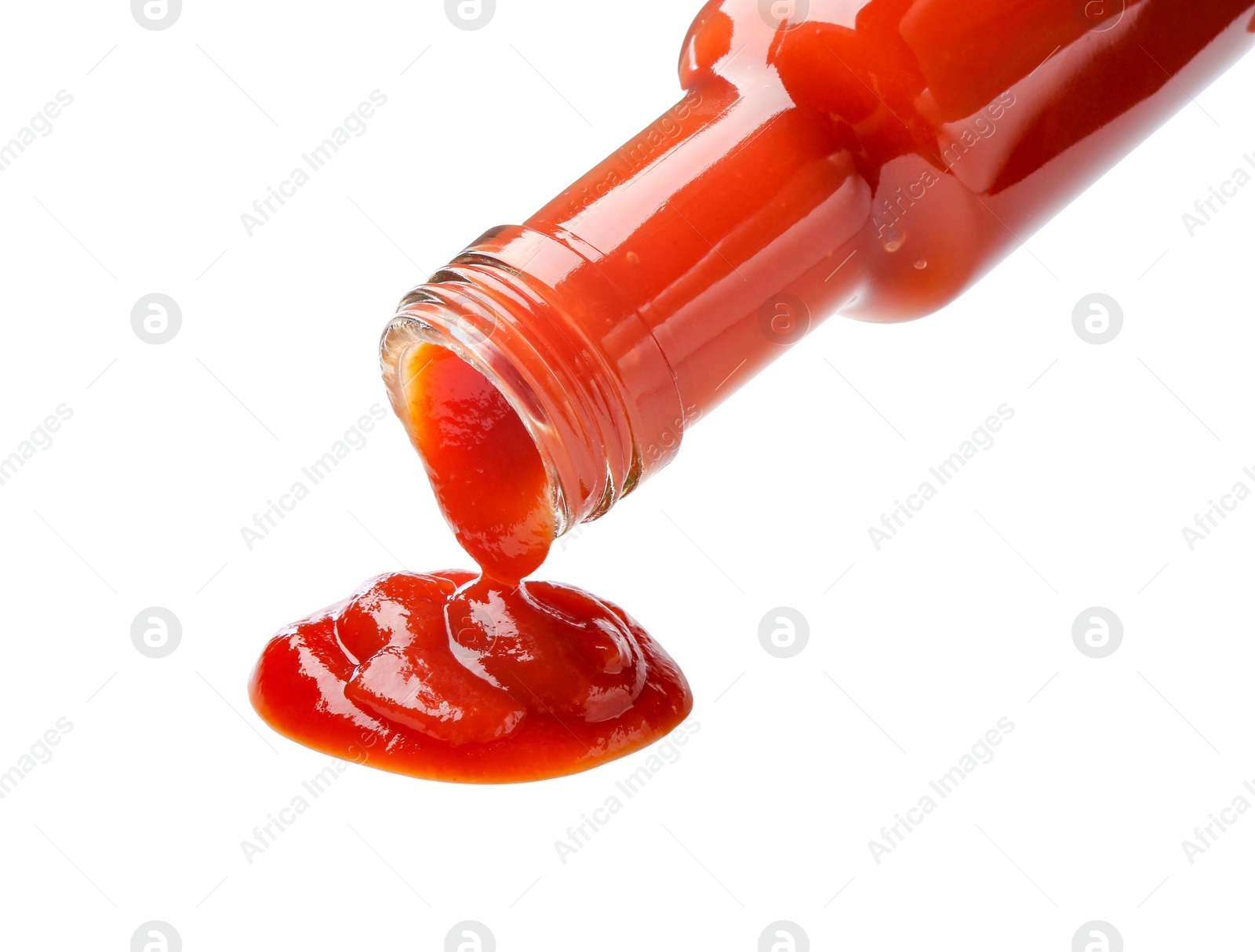 Photo of Pouring tasty ketchup from bottle isolated on white. Tomato sauce