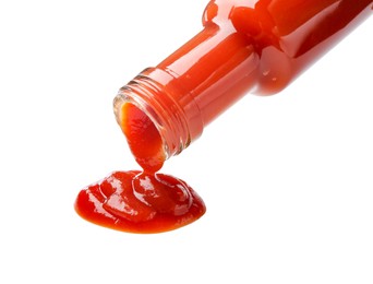 Photo of Pouring tasty ketchup from bottle isolated on white. Tomato sauce