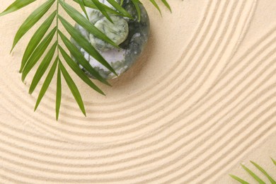 Photo of Zen concept. Stones, leaves and pattern on beige sand, flat lay. Space for text