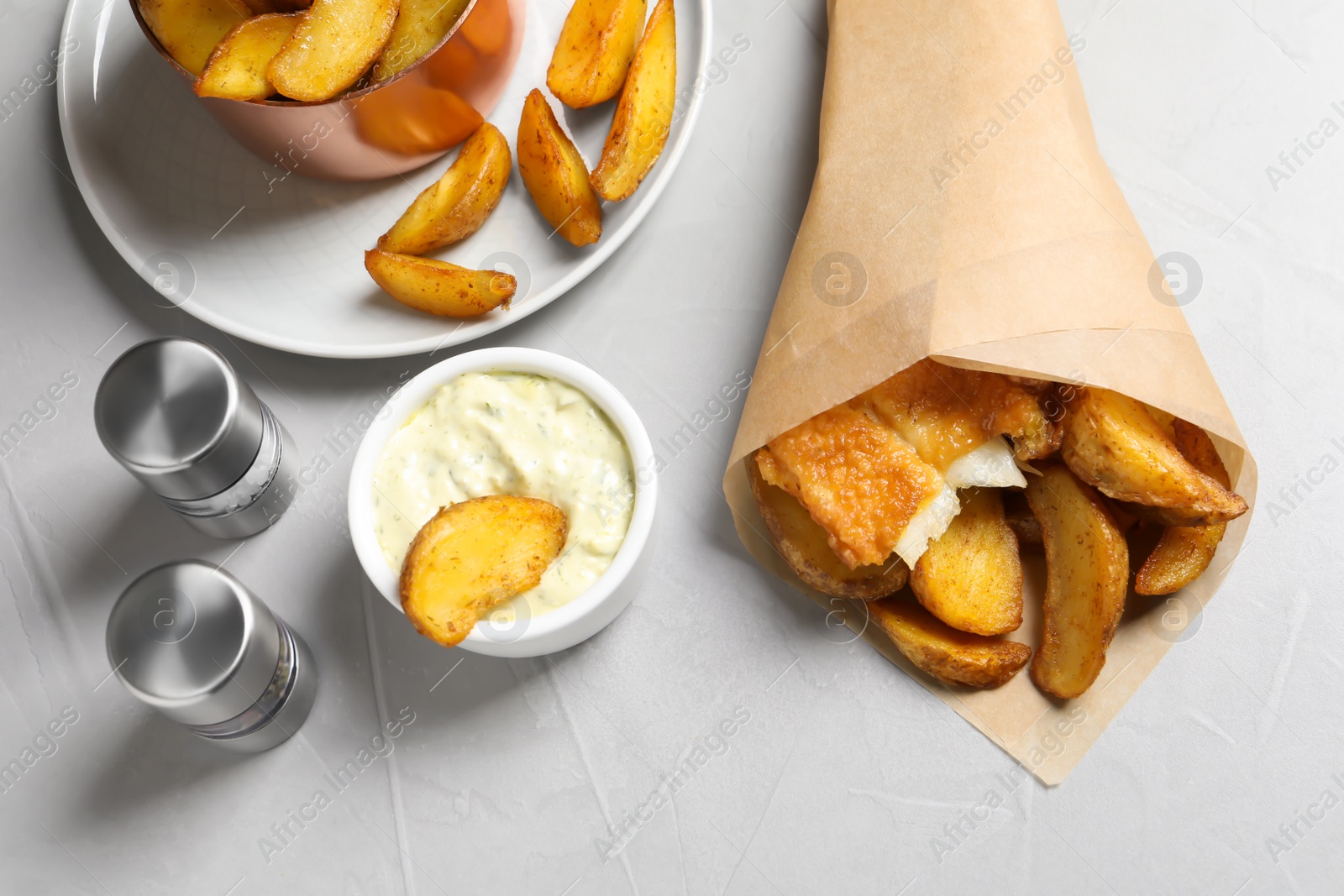 Photo of British traditional fish and potato chips in paper cone on light background, above view