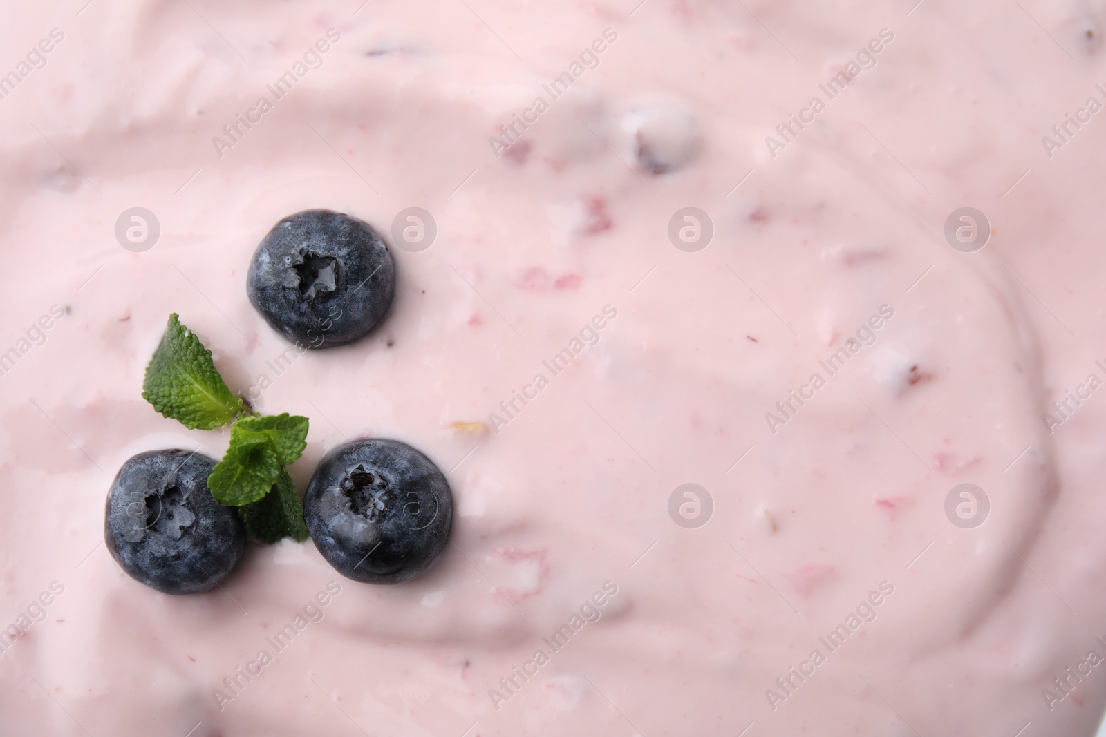 Photo of Tasty yogurt, mint and blueberries as background, top view. Space for text