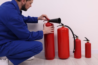 Man in uniform checking fire extinguishers indoors