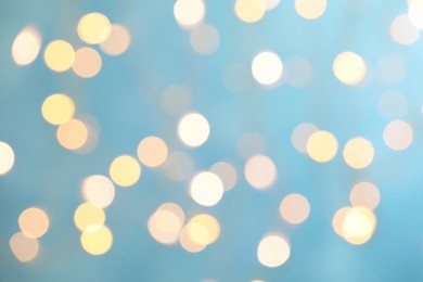 Photo of Blurred view of festive lights on light blue background. Bokeh effect