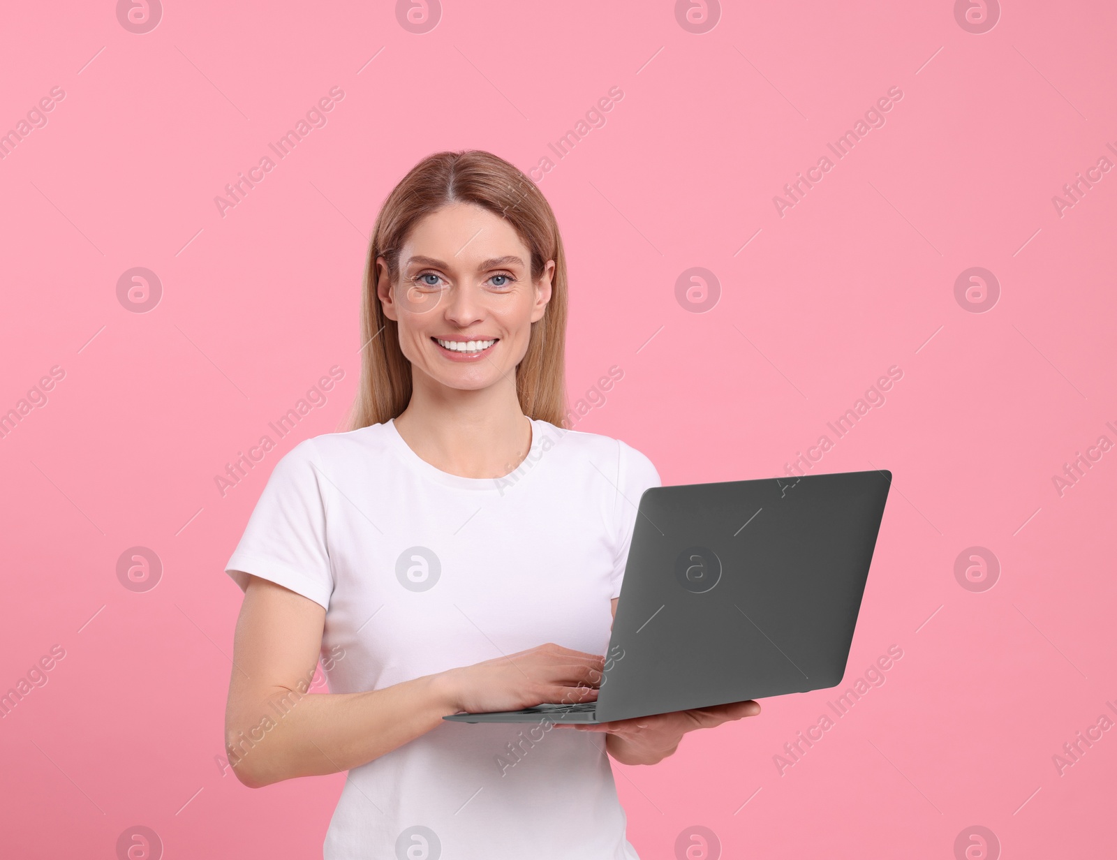 Photo of Happy woman with laptop on pink background