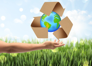 Image of Man with illustration of Earth and recycling symbol in hand, closeup