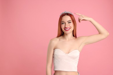 Beautiful young woman with tiara on pink background, space for text