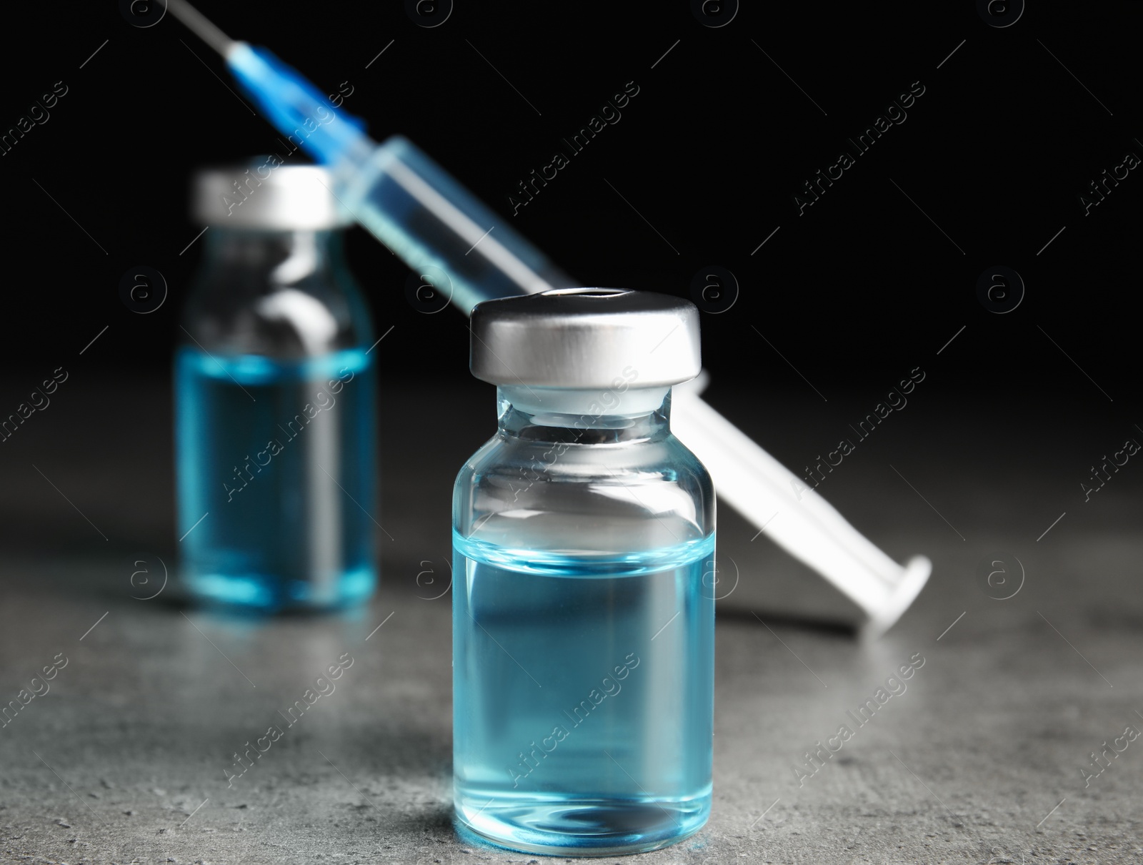 Photo of Vials and syringe on grey table. Vaccination and immunization