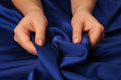 Photo of Woman touching silky blue fabric, closeup view
