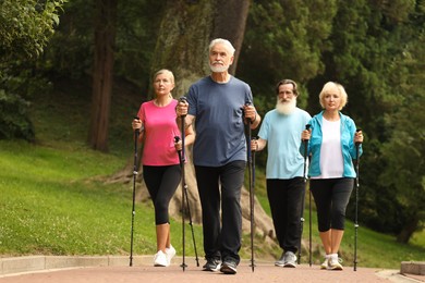 Photo of Group of senior people performing Nordic walking outdoors. Low angle view
