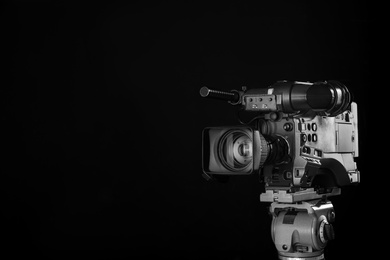 Photo of Modern professional video camera on black background. Space for text